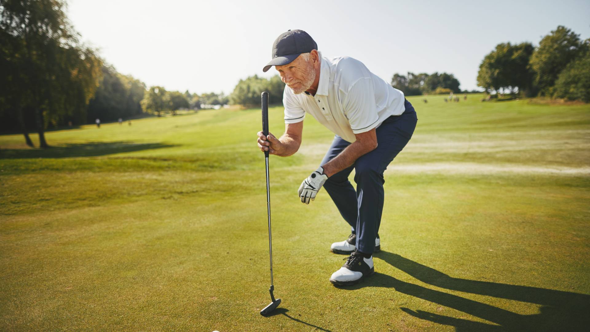 Senior Golfer Planning His Putt on a Golf Green